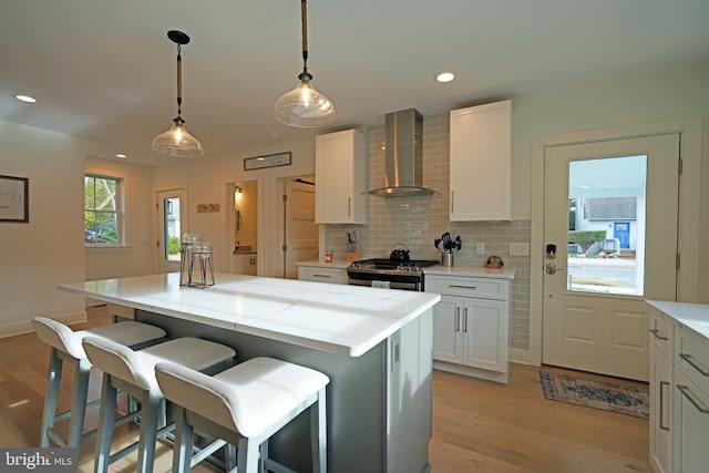 kitchen featuring a kitchen island, wall chimney exhaust hood, and white cabinets