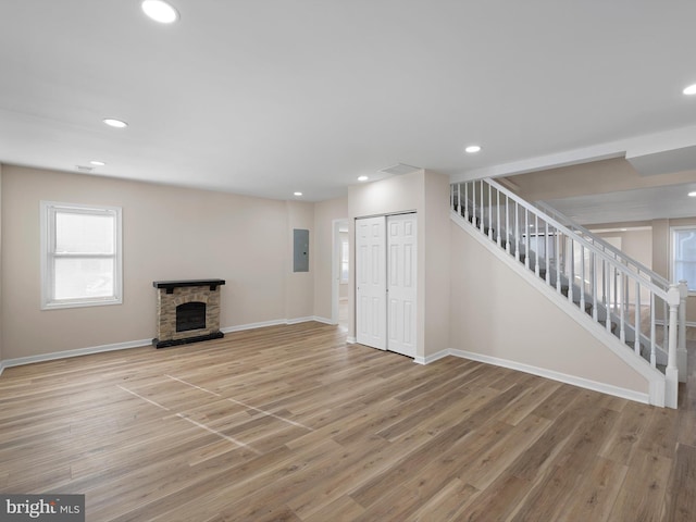 unfurnished living room featuring a fireplace, light hardwood / wood-style floors, and electric panel