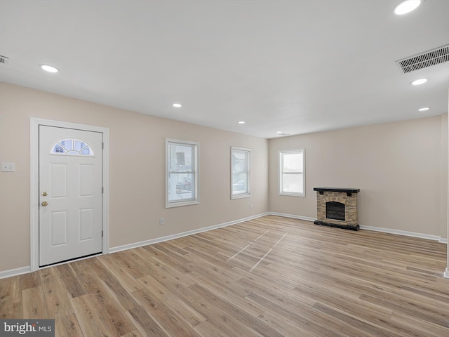 interior space with a stone fireplace and light hardwood / wood-style flooring