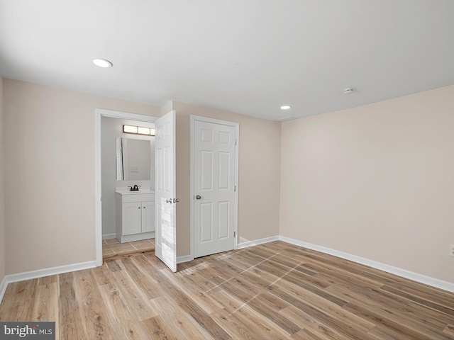 unfurnished bedroom with a closet, light hardwood / wood-style floors, and connected bathroom