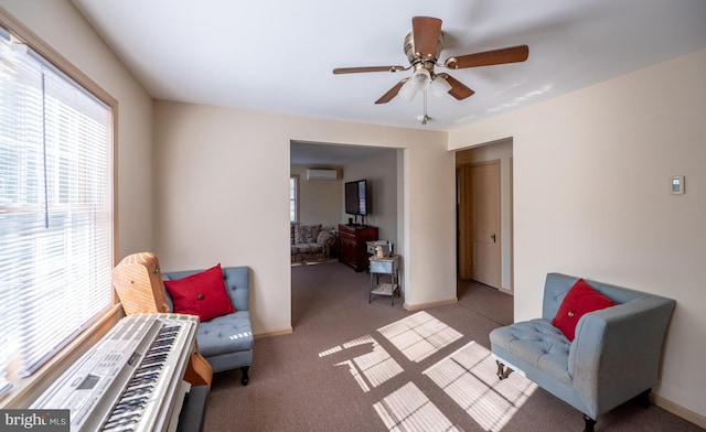 sitting room with ceiling fan, light colored carpet, and a wall mounted AC