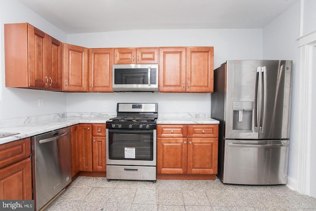 kitchen with light stone counters and appliances with stainless steel finishes