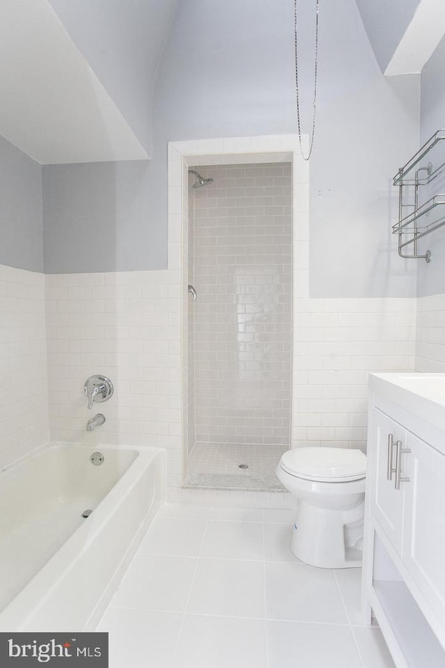 full bathroom with tile patterned flooring, tiled shower / bath, vanity, toilet, and tile walls