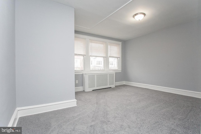 carpeted spare room featuring radiator heating unit