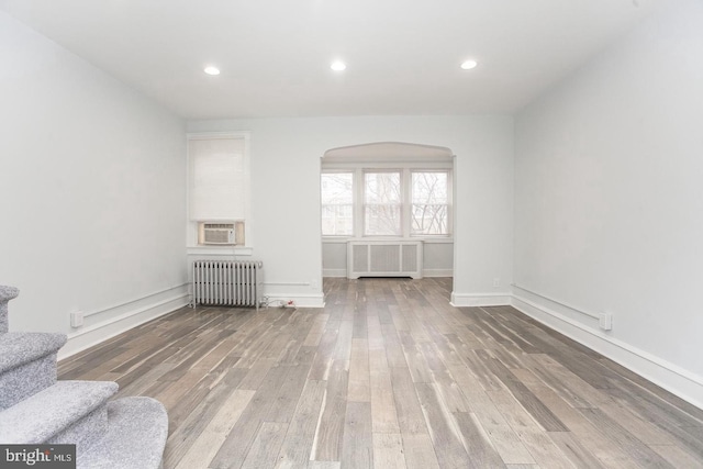 unfurnished living room with radiator heating unit, wood-type flooring, and cooling unit