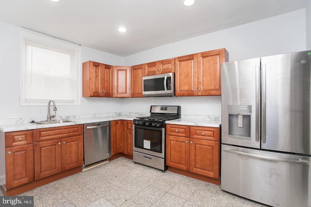 kitchen featuring sink, light stone counters, and appliances with stainless steel finishes