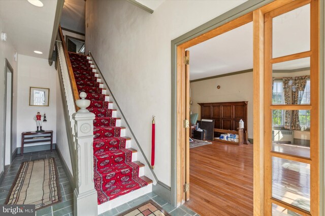 staircase with hardwood / wood-style floors and ornamental molding