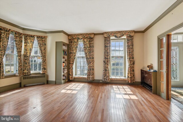 interior space with radiator, light wood-type flooring, and crown molding