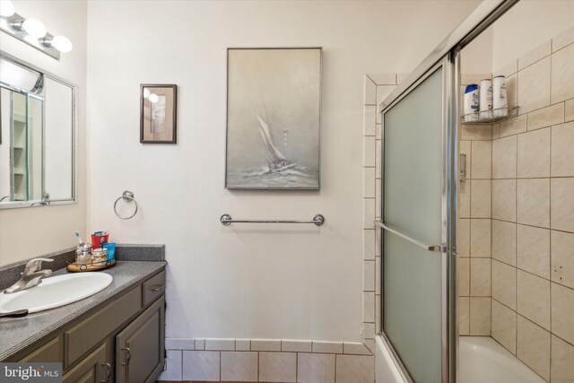 bathroom featuring shower / bath combination with glass door and vanity