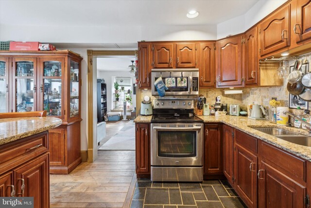 kitchen featuring sink, light stone counters, appliances with stainless steel finishes, backsplash, and dark hardwood / wood-style flooring