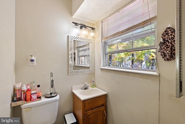 bathroom with vanity, toilet, and a textured ceiling