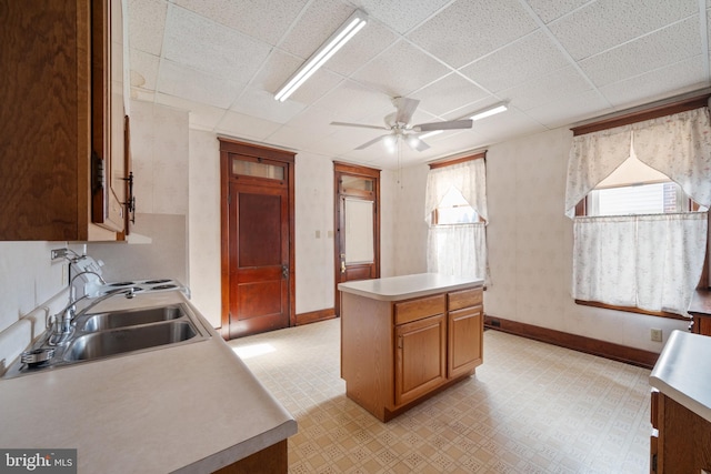 kitchen with ceiling fan, a center island, sink, and a drop ceiling