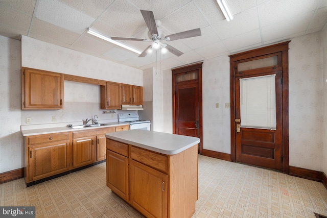 kitchen featuring sink, ceiling fan, electric range, a kitchen island, and a drop ceiling