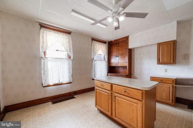 kitchen featuring ceiling fan, a center island, and a drop ceiling