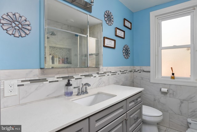 bathroom with walk in shower, vanity, toilet, and tile walls