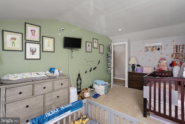 bedroom featuring a crib, carpet flooring, and lofted ceiling