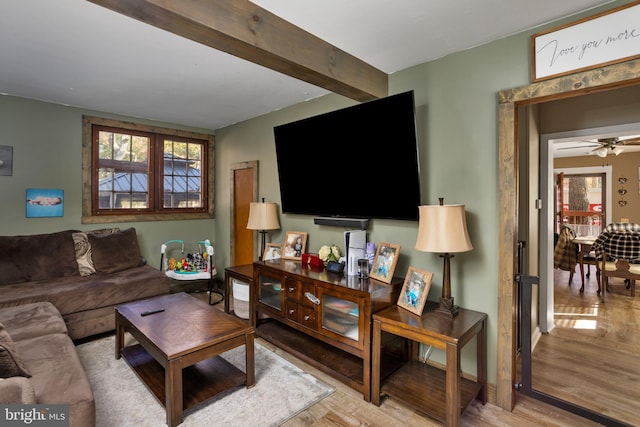 living room featuring light hardwood / wood-style flooring, beamed ceiling, and ceiling fan