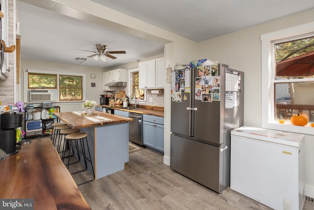 kitchen featuring stainless steel appliances, a breakfast bar area, plenty of natural light, white cabinets, and butcher block countertops