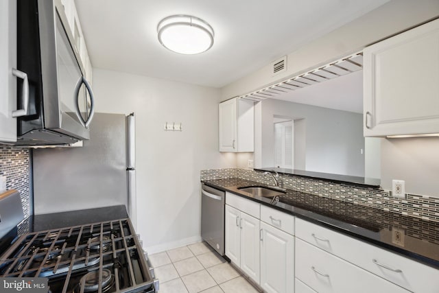 kitchen featuring sink, tasteful backsplash, light tile patterned flooring, white cabinetry, and appliances with stainless steel finishes