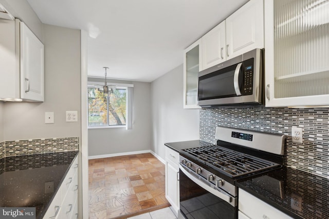 kitchen with pendant lighting, tasteful backsplash, white cabinetry, appliances with stainless steel finishes, and dark stone countertops