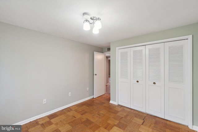 unfurnished bedroom with light parquet flooring and a closet