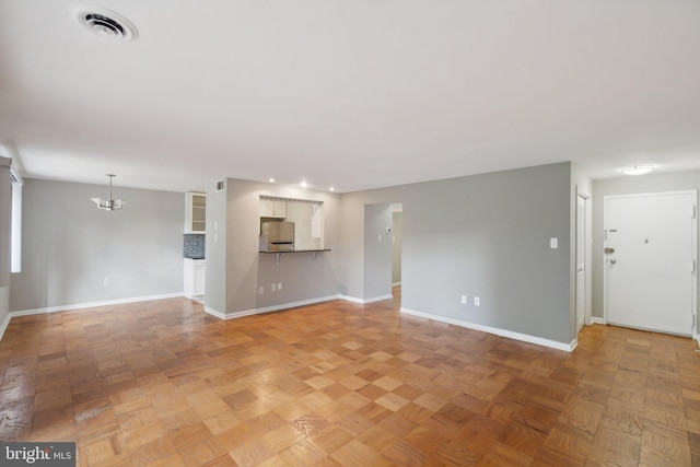 unfurnished living room featuring parquet floors and an inviting chandelier