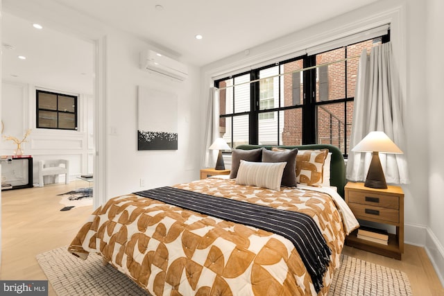 bedroom with a wall mounted air conditioner and light hardwood / wood-style floors