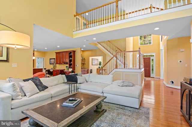 living room with a towering ceiling and light wood-type flooring