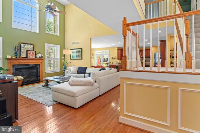 living room featuring light wood-type flooring, plenty of natural light, high vaulted ceiling, and a high end fireplace