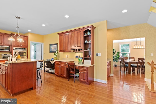 kitchen featuring light hardwood / wood-style floors, a breakfast bar, pendant lighting, and appliances with stainless steel finishes