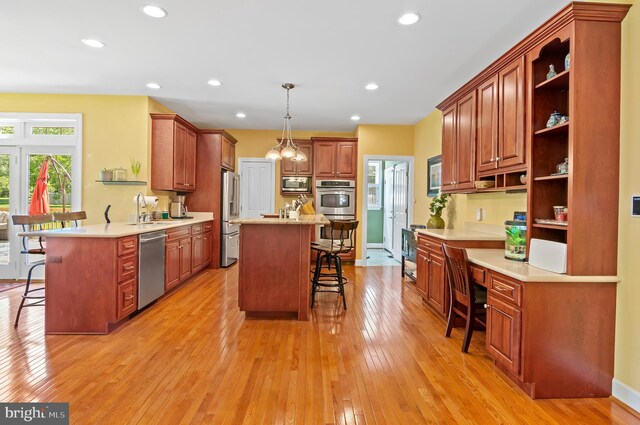 kitchen featuring light wood-type flooring, kitchen peninsula, a kitchen bar, and stainless steel appliances