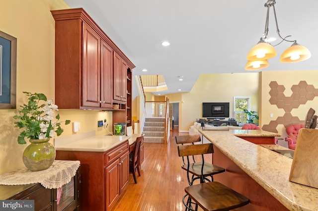 kitchen featuring light hardwood / wood-style floors, a breakfast bar, pendant lighting, and a notable chandelier