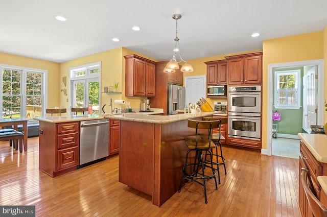 kitchen featuring kitchen peninsula, stainless steel appliances, light wood-type flooring, and a breakfast bar