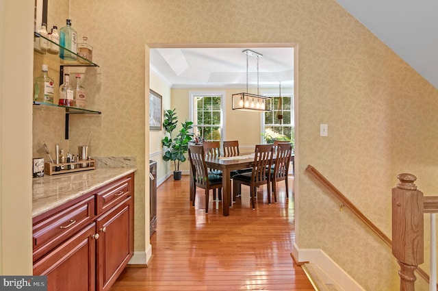 dining room with light hardwood / wood-style floors and a raised ceiling