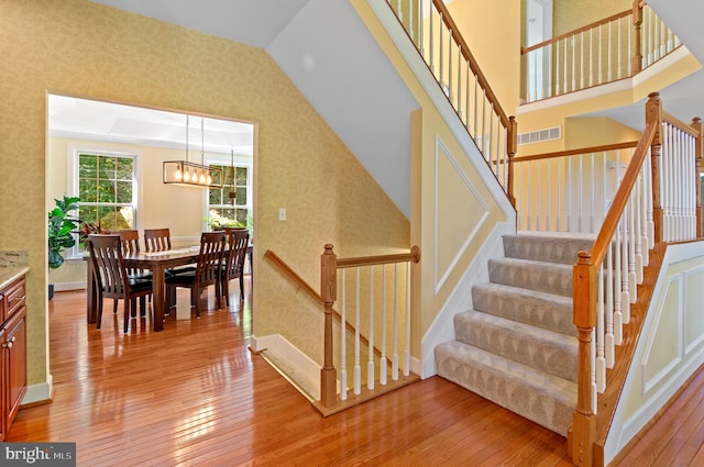 stairway featuring hardwood / wood-style floors and an inviting chandelier