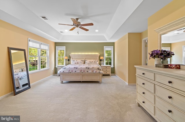 carpeted bedroom with a tray ceiling and ceiling fan