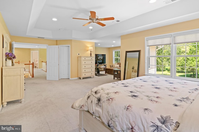 carpeted bedroom featuring ceiling fan and a raised ceiling