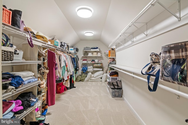 walk in closet with light carpet and vaulted ceiling