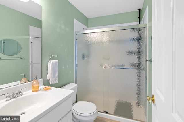 bathroom with toilet, vanity, and a shower with shower door