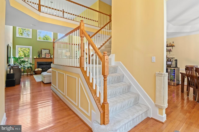 stairs with crown molding, wood-type flooring, and a high ceiling