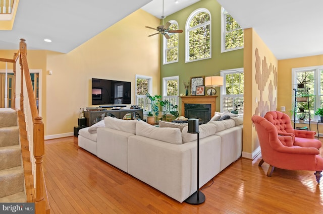 living room featuring light hardwood / wood-style flooring, high vaulted ceiling, ceiling fan, and plenty of natural light