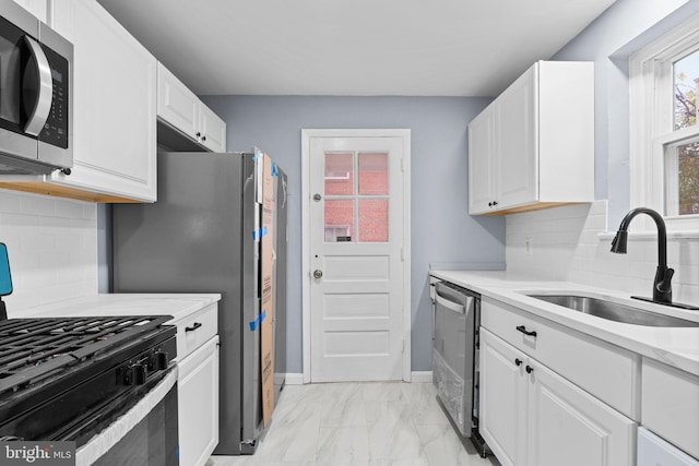 kitchen featuring appliances with stainless steel finishes, tasteful backsplash, white cabinetry, and sink