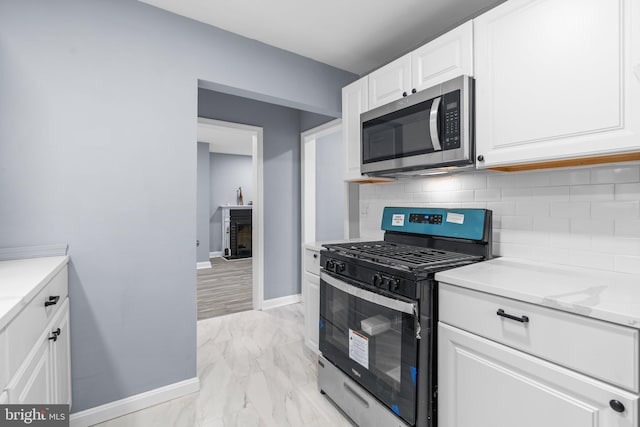 kitchen with decorative backsplash, light stone counters, white cabinetry, and gas range