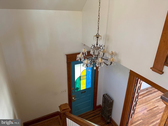 entrance foyer featuring radiator, a towering ceiling, hardwood / wood-style flooring, and a notable chandelier