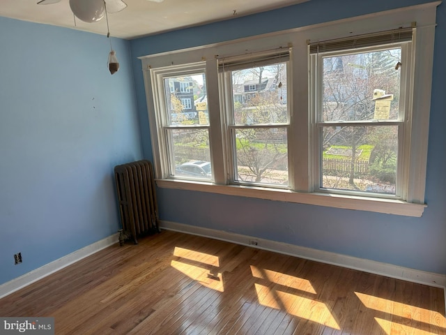 spare room featuring hardwood / wood-style floors, ceiling fan, and radiator