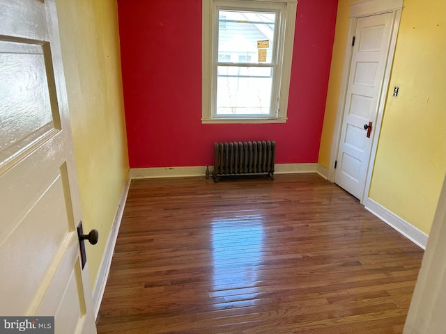 spare room with dark wood-type flooring and radiator heating unit