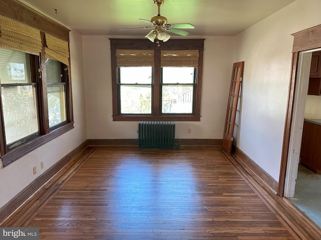 unfurnished room with ceiling fan, dark hardwood / wood-style floors, and radiator heating unit