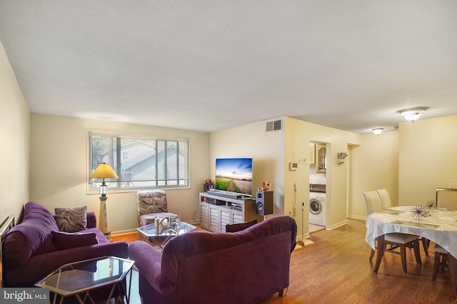 living room with washer / clothes dryer and wood-type flooring