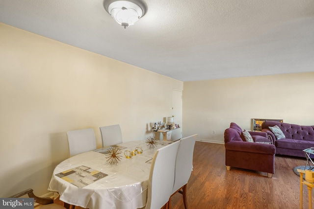 dining room featuring a textured ceiling and dark hardwood / wood-style floors