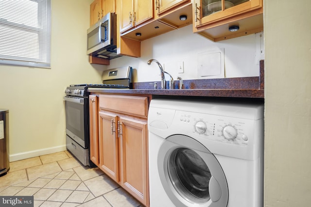 kitchen featuring sink, light tile patterned floors, stainless steel appliances, and washer / dryer